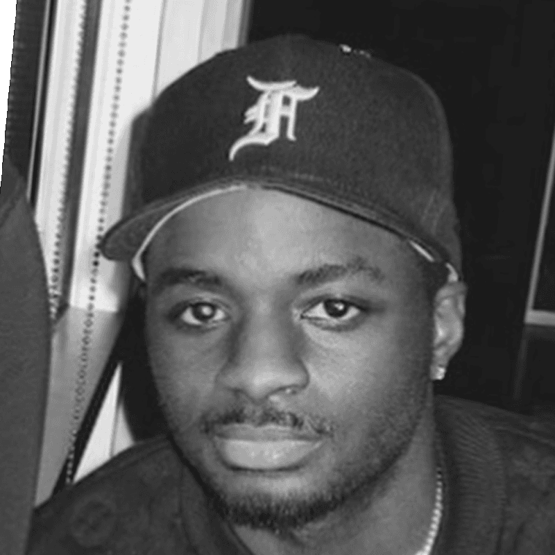 Black and white photo of Shay in a fitted cap, looking straight at the camera.